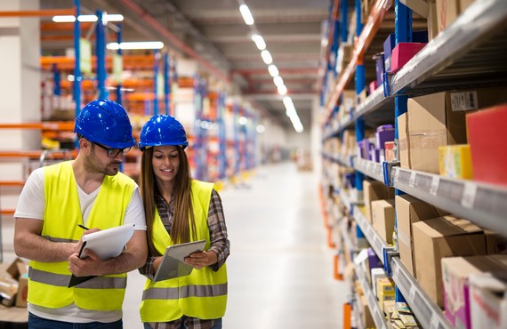 Warehouse employees working together on counting products and checking inventory in storage center.